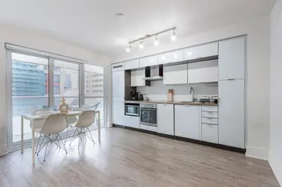 a kitchen with white cabinets and a table and chairs at Downtown CN Tower View Condo with Pool Hot tub and Gym in Toronto