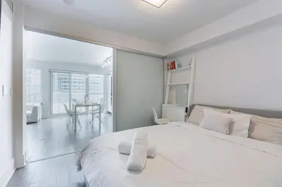 a white bedroom with a large bed and a table at Downtown CN Tower View Condo with Pool Hot tub and Gym in Toronto