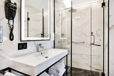 a white bathroom with a sink and a shower at Riu Plaza Toronto in Toronto