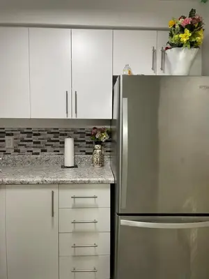 a kitchen with white cabinets and a stainless steel refrigerator at The Basics - Private Room in Toronto