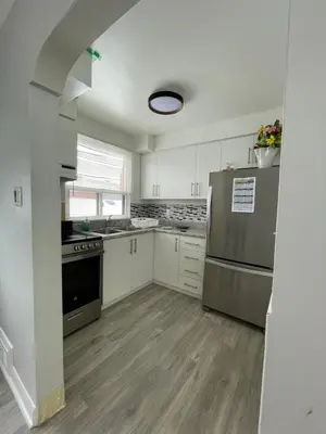 a kitchen with white cabinets and a stainless steel refrigerator at The Basics - Private Room in Toronto
