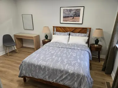 a bedroom with a bed and two tables and a chair at Streetsville Retreat - Prime Location in Mississauga
