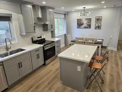 a kitchen with white cabinets and a kitchen island with a table at Streetsville Retreat - Prime Location in Mississauga