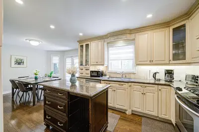 a kitchen with wooden cabinets and a table with chairs at Upper-Level Classic House in Richmond Hill in Richmond Hill