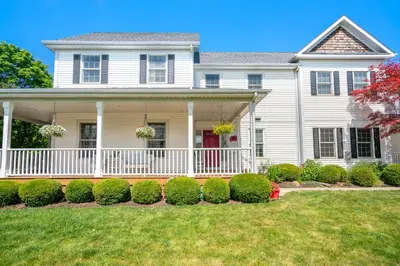 a white house with a porch and bushes at John & Gate House boutique Bed and Breakfast in Niagara on the Lake