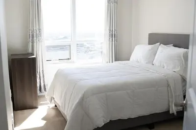 a white bed in a bedroom with a window at Spacious 2 bedrooms 2 bathrooms with Cozy Charm plus 1 Parking in Mississauga
