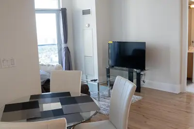 a living room with a table and chairs and a television at Spacious 2 bedrooms 2 bathrooms with Cozy Charm plus 1 Parking in Mississauga