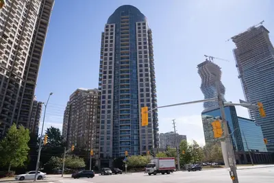 a large tall building in a city with cars at Spacious 2 bedrooms 2 bathrooms with Cozy Charm plus 1 Parking in Mississauga