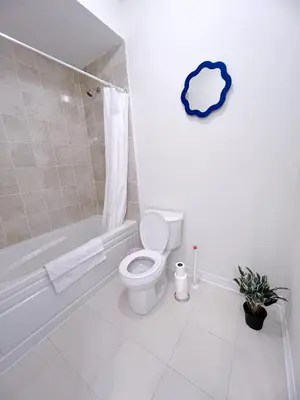 a white bathroom with a toilet and a bath tub at Modern entire house close to Costco convenient stay in Richmond Hill