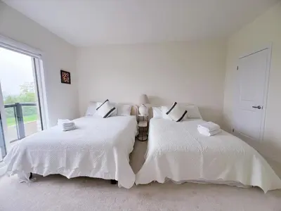 two beds in a white bedroom with a window at Modern entire house close to Costco convenient stay in Richmond Hill