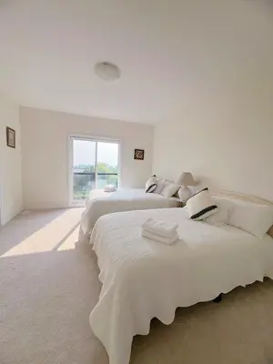 two beds in a white room with a window at Modern entire house close to Costco convenient stay in Richmond Hill