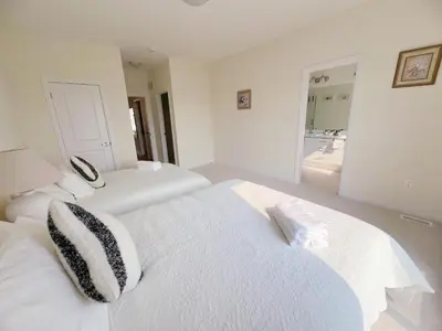 a white bedroom with two beds and a mirror at Modern entire house close to Costco convenient stay in Richmond Hill