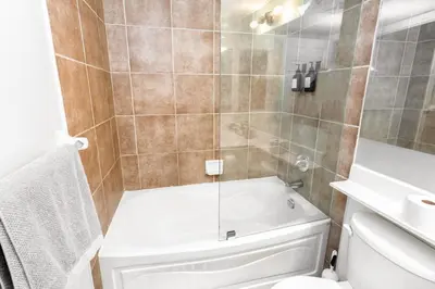 a bathroom with a shower with a tub and a toilet at Sky Retreat | 2BR-2BA High Floor | 180° City View in Mississauga