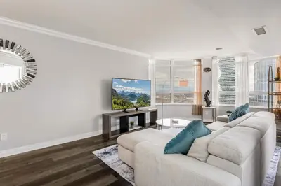 a living room with a white couch and a tv at Sky Retreat | 2BR-2BA High Floor | 180° City View in Mississauga