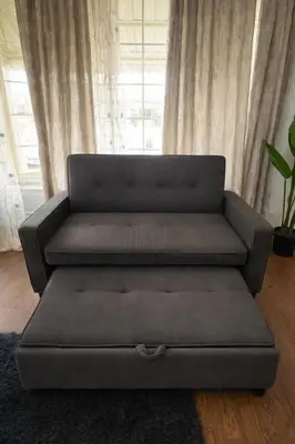 a couch sitting in a living room with a window at Newly Renovated 3BR North York Bungalow with Backyard Patio & Volleyball Set! Close to Rogers Stadium, TTC Subway Access, Perfect for Family Travel, Group Trips & Work Stays! in Toronto