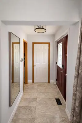 a hallway with two doors and a mirror at Newly Renovated 3BR North York Bungalow with Backyard Patio & Volleyball Set! Close to Rogers Stadium, TTC Subway Access, Perfect for Family Travel, Group Trips & Work Stays! in Toronto