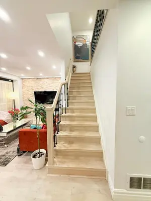 a staircase in a home with white walls and wooden floors at Welcome to Your Home Away From Home! in Mississauga