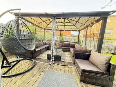 a patio with a couch and swings under an umbrella at Welcome to Your Home Away From Home! in Mississauga