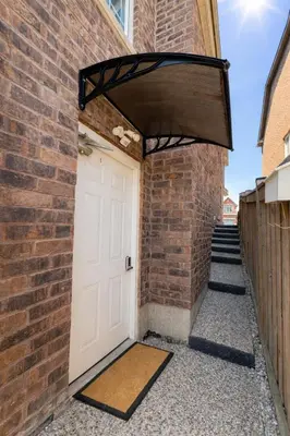 a brick building with a white door and a brick wall at Cozy 3BR Caledon Basement Suite with Private Access, Full Kitchen, WiFi, Laundry, Backyard Basketball Court & Creek Trail, 5 Mins to Brampton! Great for Families & Long Stays! in Caledon