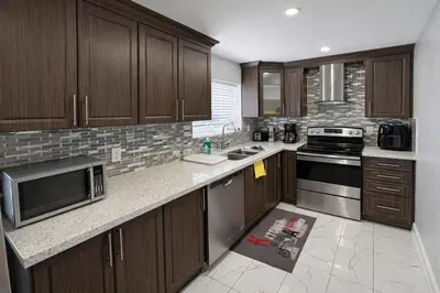 a kitchen with wooden cabinets and a counter top at Cozy 3BR Caledon Basement Suite with Private Access, Full Kitchen, WiFi, Laundry, Backyard Basketball Court & Creek Trail, 5 Mins to Brampton! Great for Families & Long Stays! in Caledon