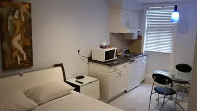 a bedroom with a bed and a kitchen with a microwave at Dragon Gate Inn in Toronto