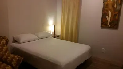 a bedroom with a white bed and a lamp on a table at Dragon Gate Inn in Toronto