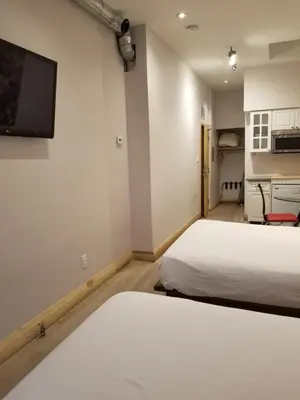 a bedroom with two beds and a flat screen tv at Dragon Gate Inn in Toronto
