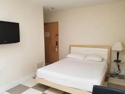 a bedroom with a bed and a flat screen tv at Dragon Gate Inn in Toronto