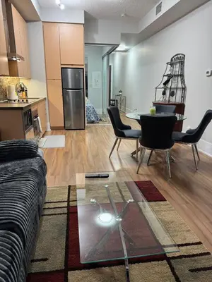 a living room with a couch and a table and a kitchen at Downtown Toronto Condo with CN Tower View in Toronto