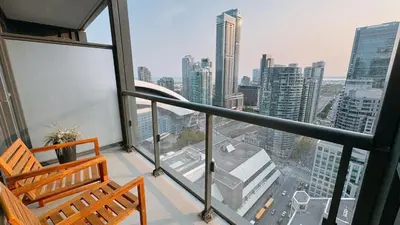 a balcony with two chairs and a view of a city at Luxury 1 BR and Den Near CN Tower in Toronto