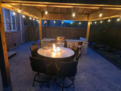 a patio with a table and chairs and lights at Your Luxurious Caledon Escape in Brampton