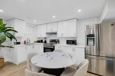 a kitchen with white cabinets and a table with chairs at Your Luxurious Caledon Escape in Brampton
