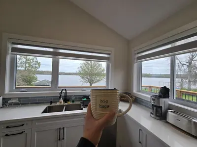 a person holding up a mug in a kitchen at Wheel chair Access, Private Boat Launch in Roseneath