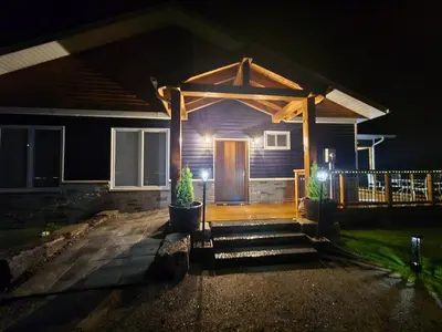 a house with a wooden front door at night at Wheel chair Access, Private Boat Launch in Roseneath