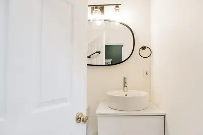a white bathroom with a sink and a mirror at The Parkdale Cottage in Toronto