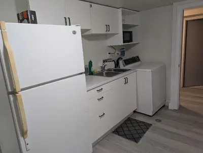 a white kitchen with a sink and a refrigerator at Cozy Bachelor Unit in Guelph