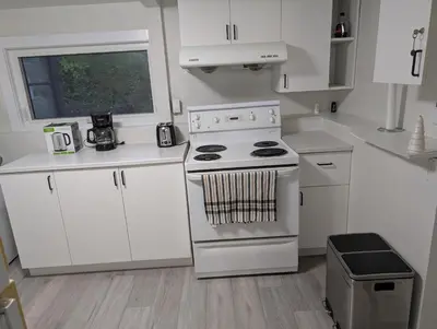 a white kitchen with a stove and white cabinets at Cozy Bachelor Unit in Guelph
