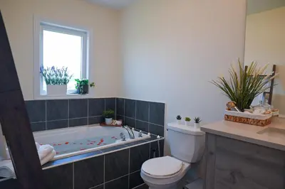 a bathroom with a tub and a toilet and a sink at Modern 3Bed Home 10 Mins to Niagra Falls in Thorold