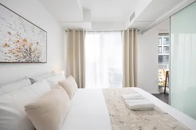 a white bedroom with a white bed and a window at Classy and Luxury 2 bedroom apartment 5 mins to Dundas Square in Toronto