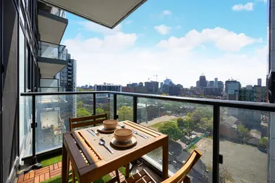 a balcony with a wooden table and a view of the city at Classy and Luxury 2 bedroom apartment 5 mins to Dundas Square in Toronto