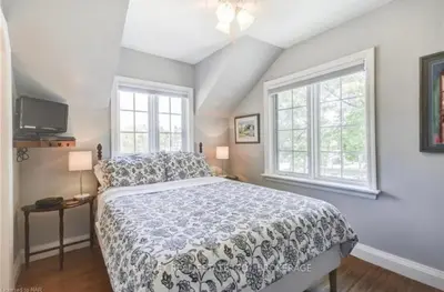 a bedroom with a large bed and two windows at Matisse B&B in Niagara on the Lake