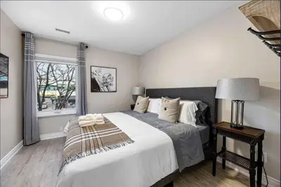a bedroom with a large bed and a window at Casa Hotel Contemporary 2BR Suite w Patio & BBQ in Toronto