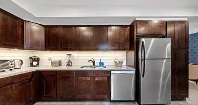 a kitchen with wooden cabinets and a stainless steel refrigerator at Casa Hotel Contemporary 2BR Suite w Patio & BBQ in Toronto