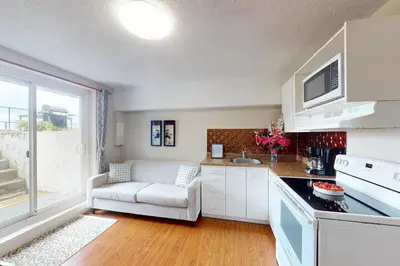 a kitchen with white cabinets and a chair and a window at The Driftwood Deck in Wasaga Beach