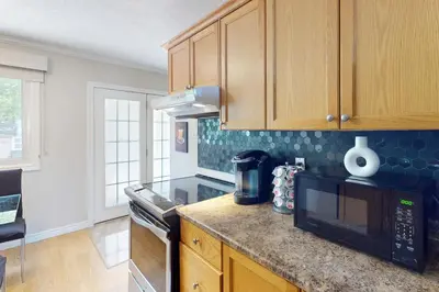 a kitchen with wooden cabinets and a black microwave at The Driftwood Deck 5A in Wasaga Beach