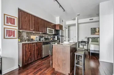 an apartment kitchen with wooden cabinets and a bed at Spacious 2BR Condo Downtown, Lakeshore, Parking in Toronto