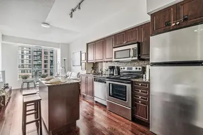a kitchen with wooden cabinets and stainless steel appliances at Spacious 2BR Condo Downtown, Lakeshore, Parking in Toronto