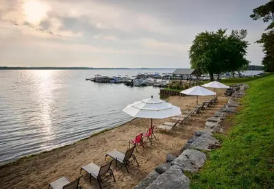 a group of chairs and umbrellas on a beach at Bobcaygeon Shores Cottage Resort in Kawartha Lakes
