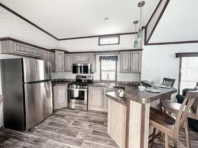 a kitchen with wooden cabinets and a stainless steel refrigerator at Bobcaygeon Shores Cottage Resort in Kawartha Lakes