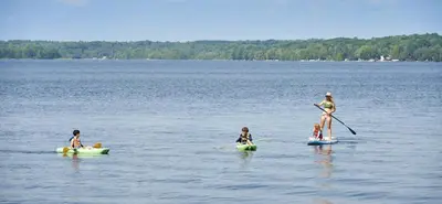 a woman and three children in a large body of water at Bobcaygeon Shores Cottage Resort in Kawartha Lakes